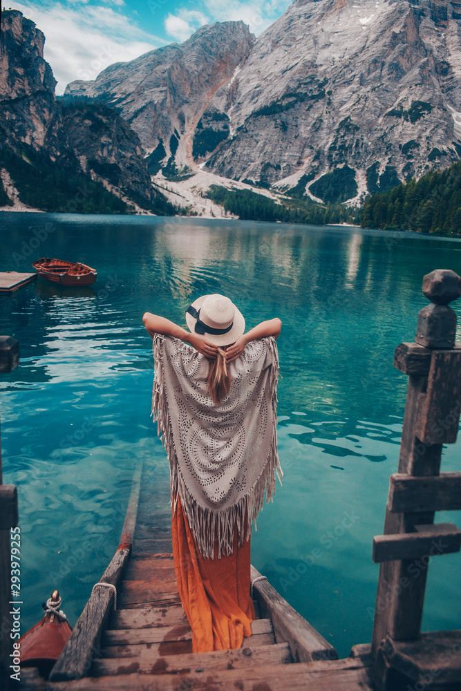 Wall mural girl in a straw hat on the background of the turquoise lake with wooden boats in mountains. safari s