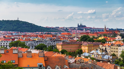 Naklejka na ściany i meble View of Prague Castle over red roof from Vysehrad area at sunset lights, Prague, Czech Republic. Scenic view of Prague city, Prague castle and Petrin tower from Vysehrad overlooking red roofs
