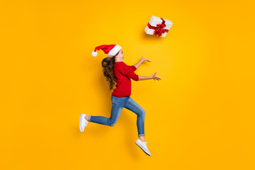 Fototapeta na wymiar Full body profile photo of crazy little lady jumping high catching big giftbox excited to what what inside wear red knitted pullover isolated yellow background
