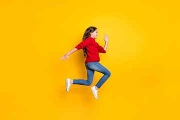 Fototapeta na wymiar Full body profile side photo of positive cheerful model kid jump run fast speedy after black friday bargains wear red stylish pullover denim jeans white sneakers isolated over yellow color background