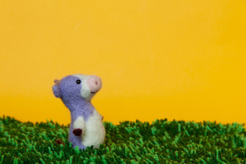 草原風の緑のマット、フェルトの牛（横向き）黄色背景