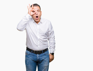 Middle age arab elegant man over isolated background doing ok gesture shocked with surprised face, eye looking through fingers. Unbelieving expression.