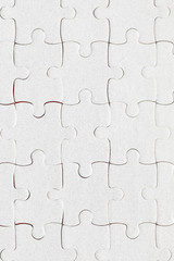 Fototapeta premium Unfinished white jigsaw puzzle pieces. Fill in pieces of the jigsaw puzzle. Complete the jigsaw puzzle with the missing pieces. Fragment of a folded white jigsaw puzzle.