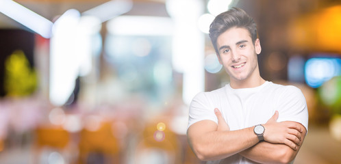 Young handsome man wearing white t-shirt over isolated background happy face smiling with crossed arms looking at the camera. Positive person.