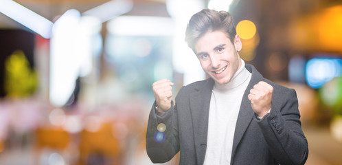 Young elegant man wearing winter coat over isolated background celebrating surprised and amazed for success with arms raised and open eyes. Winner concept.