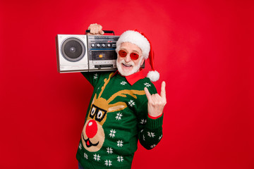 Photo of elderly funny santa man holding vintage tape recorder at youngster party show horns wear...
