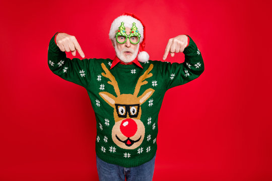 Photo of santa looking on low x-mas shopping prices indicate fingers on cheap jumper wear x-mas tree shape specs ugly ornament sweater isolated red background