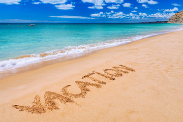 Vacation text on a beach. Vacation written in a sandy tropical beach. 