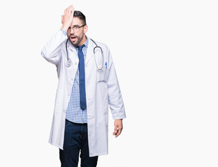 Handsome young doctor man over isolated background surprised with hand on head for mistake,...