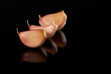 three cloves garlic lie on black mirror the surface