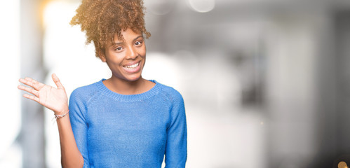 Beautiful young african american woman over isolated background Waiving saying hello happy and smiling, friendly welcome gesture