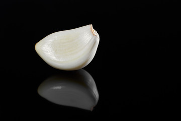 garlic clove peeled on black mirror surface