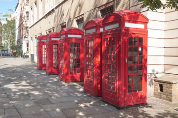 Typical red telephone booths on sunny street in London