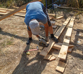 A worker cuts a wooden board at a construction site