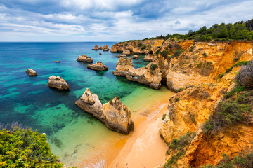 View of stunning beach with golden color rocks in Alvor town , Algarve, Portugal. View of cliff...