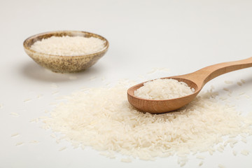 white rice in a plate on a white table and in a wooden spoon