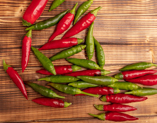 Green and red chili peppers on a wooden board