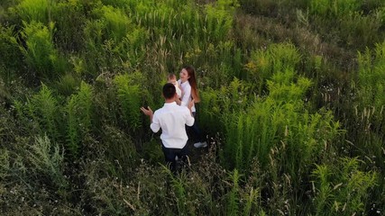 Beautiful view from the drone to the happy young family playing with baby among the meadow.