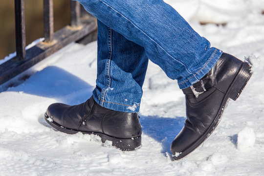 Legs of a man in shoes and jeans on the snow in winter