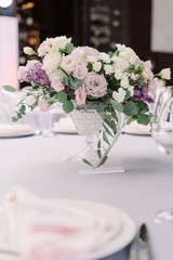 Beautiful flowers in a crystal vase decorate a festive table for guests of the groom and bride in the restaurant