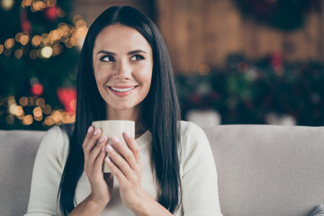 Close up photo of positive cheerful festive girl sit on divan sofa hold mug with hot beverage enjoy...