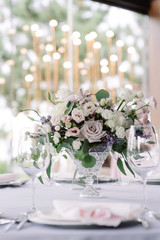 Elegant flowers in a glass vase decorate a wedding table for guests of the groom and bride in the restaurant
