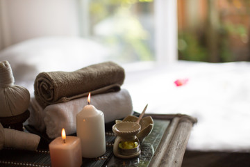 Fototapeta na wymiar Spa treatments on White spa massage bed with candles, massage oil and Herbal massage cubes