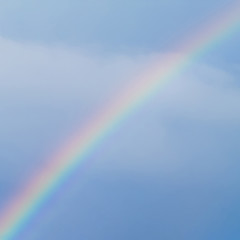 Real rainbow in cloudy blue sky