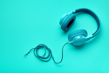 Turquoise headphones a colored background. Music concept with copyspace. Blue headphones isolated