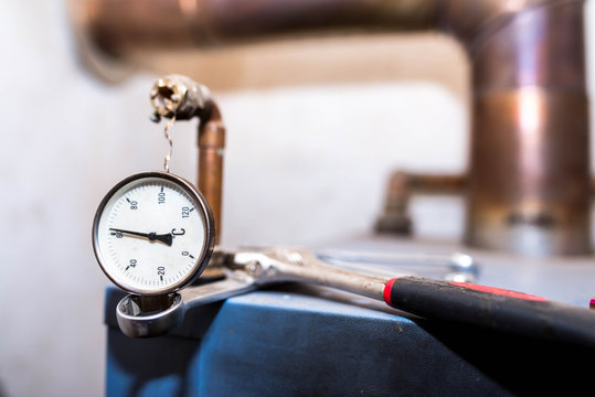 Broken Thermometer On Wood Central Heating System's Top, Wrenches In  Different Sizes On The Blurred Background.