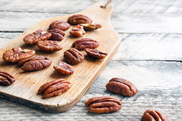 Pecan nuts on kitchen wooden board. Selective focus. 