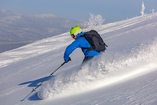 freerider in a bright suit rides fast skiing with large splashes of snow on a sunny day. very high resolution and photo quality Skiing. Snow scoot. Extreme winter sports