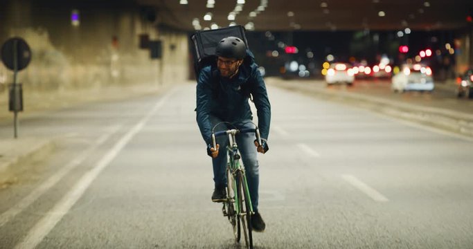Slow motion of an young delivery courier with bicycle is touching a futuristic screen with augmented reality hologram maps to view the addresses of customers in the evening in a city center.