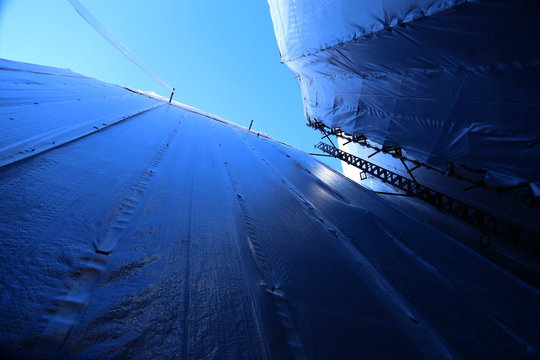 Construction work on old brick house with scaffolding, tarps, cement etc