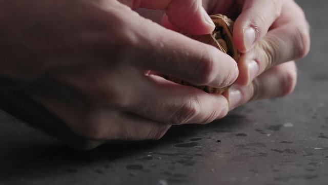Slow motion closeup man hands opens walnut
