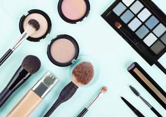 Set of woman's cosmetics on blue background. Women's secrets. Decorative cosmetics: highlighter, concealer, rouge, palette with eye shadows and brushes for face make up, face sculpture . Make up.