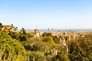 Fototapeta na wymiar Spring Barcelona general view from mountain Montjuic. Beautiful urban landscape with green hills, gardens, trees, red roofs for architectural print, poster. Bright springtime on Mediterranian sea