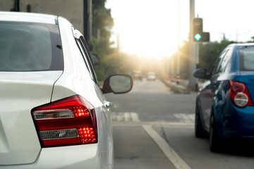 Fototapeta premium Luxury of white car stop on the asphalt road. Traveling in the provinces during the bright period. Open light brake and released on green traffic lights.