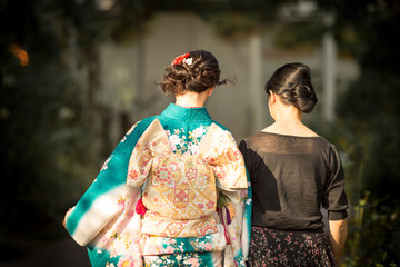 A Japanese woman wearing kimono accompanied by another woman in black dress. 