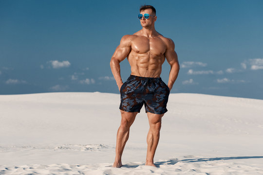 Muscular man on the beach. Strong male naked torso abs outdoors