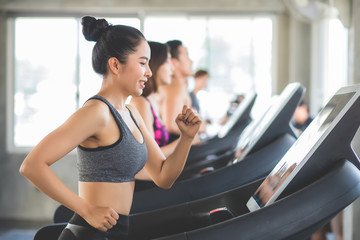 Fototapeta na wymiar Beautiful Asian women Thai people have tan skin, long hair and tied hair in a sports bra doing exercise by running on the electric treadmill in the fitness room in Thailand.