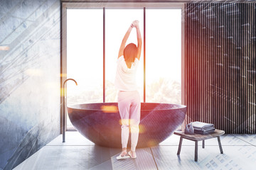 Woman in concrete and wooden bathroom