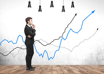 Thoughtful businessman in room with growing graphs
