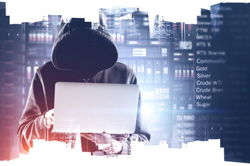 Hooded hacker with laptop in city