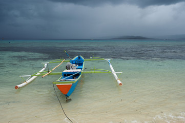 Outrigger canoe under tropical rain storm, Gangga Island, Sulawesi Indonesia.