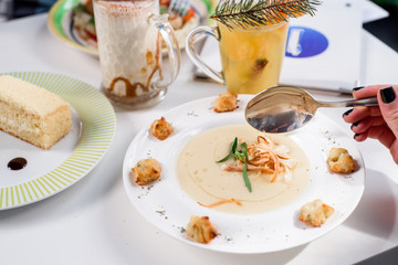 Conceptual cream soup in a white plate on a white table in a restaurant, cool plan. space