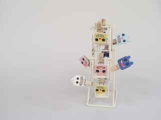 Tiny cloth pegs which are colorful painted into little monster face simulated on little white ferris wheel.