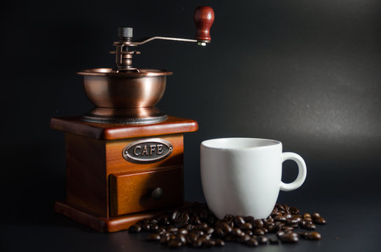 white coffee cup and coffee grinder and coffee beans on black background