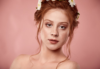 Naklejka premium Beautiful positive redheaded girl with a chamomile crown on her head