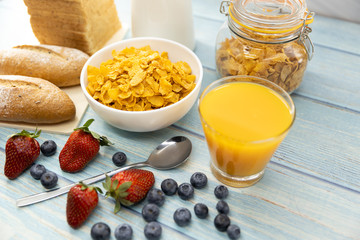 Healthy breakfast. bread, orange juice, strawberry, blueberries, milk and cereal in bowl on wooden table. Healthy food